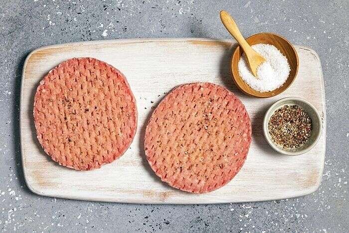 Frozen beef burger patties seasoned with salt and pepper