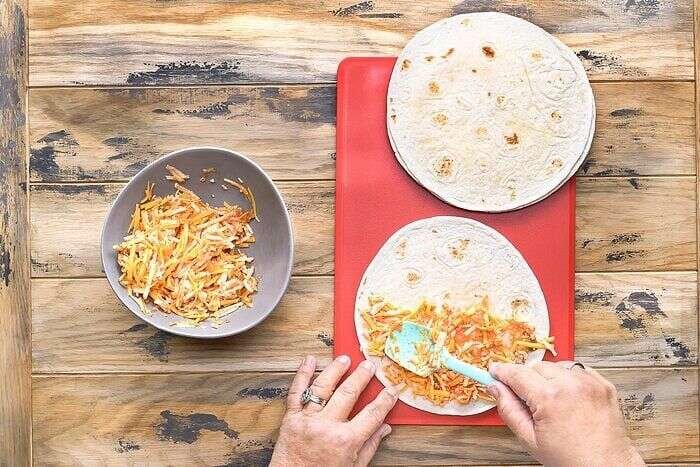 Cheese and salsa filling spread over a flour tortilla for quesadillas