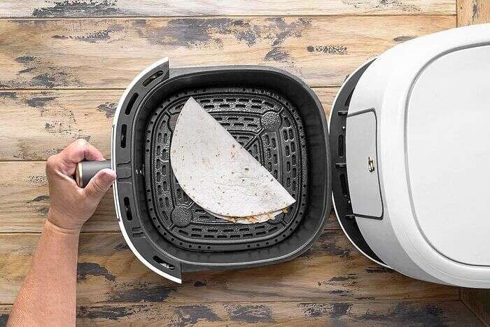 Folded quesadilla placed in an air-fryer basket before cooking