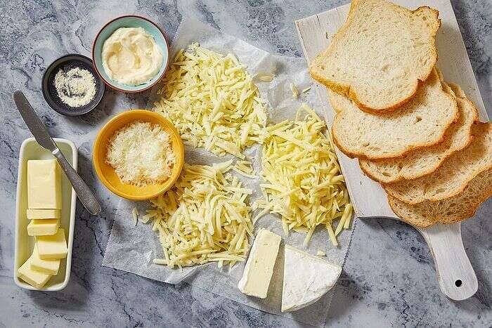 Grilled cheese sandwich ingredients with sourdough, butter, mayonnaise, Brie, and shredded cheeses