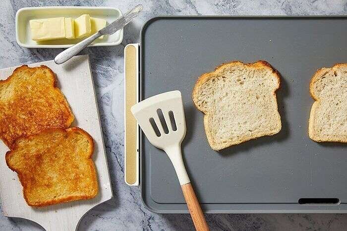 Sourdough bread slices being pre-toasted for grilled cheese sandwiches