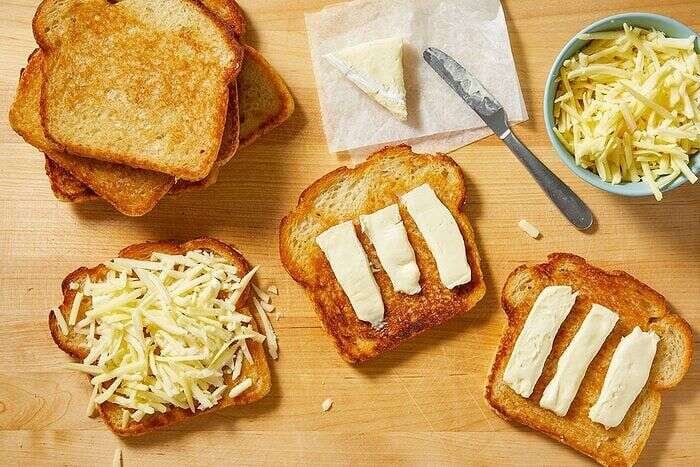 Brie and shredded cheese layered onto toasted bread for grilled cheese