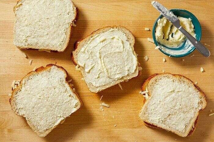 Grilled cheese sandwiches assembled with bread, creamy coating, and shredded cheese