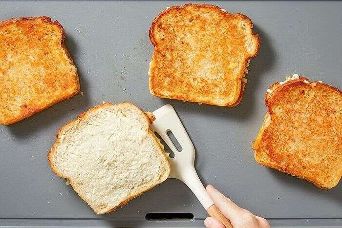 Grilled cheese sandwiches cooking on a griddle until golden brown