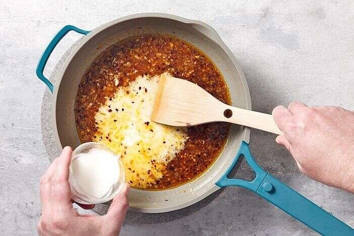 Orange chicken sauce cooking with ginger, garlic, and spices
