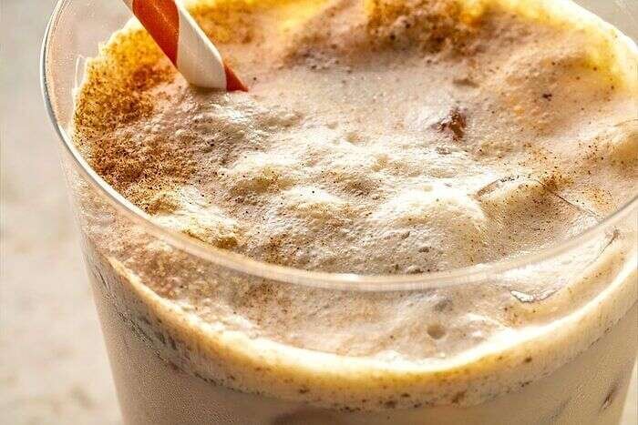 Creamy iced pumpkin cream chai latte with cinnamon topping