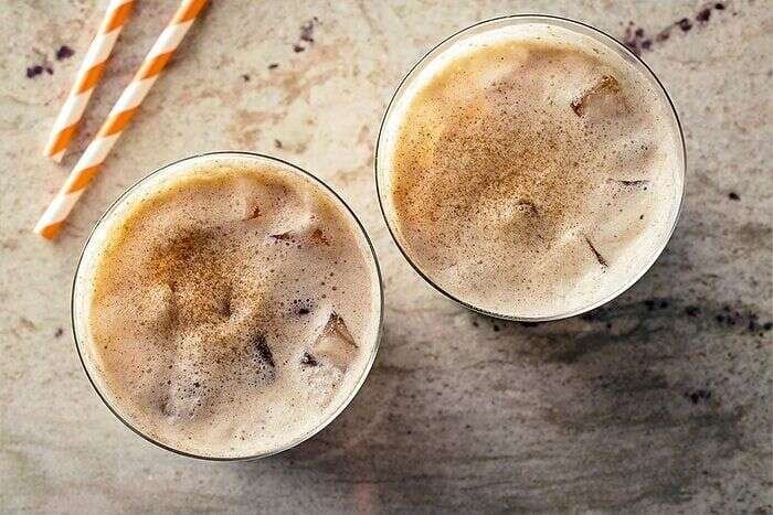 Iced pumpkin cream chai latte topped with foam and pumpkin spice