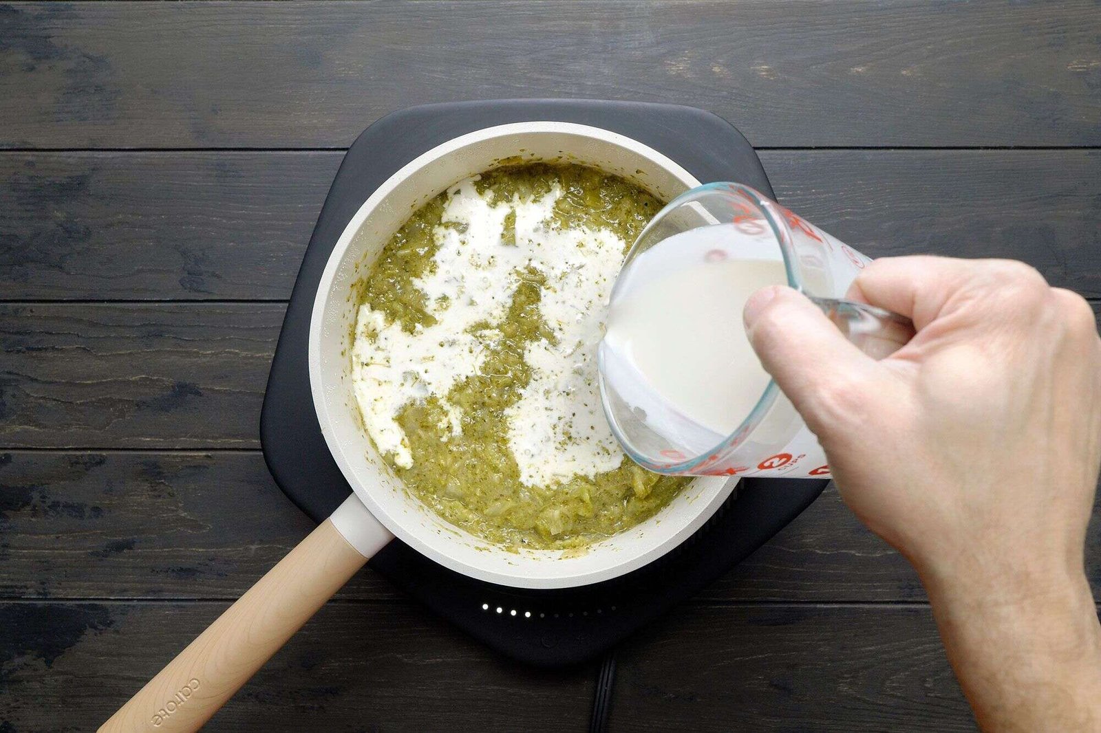 Heavy cream being stirred into thickened broccoli soup