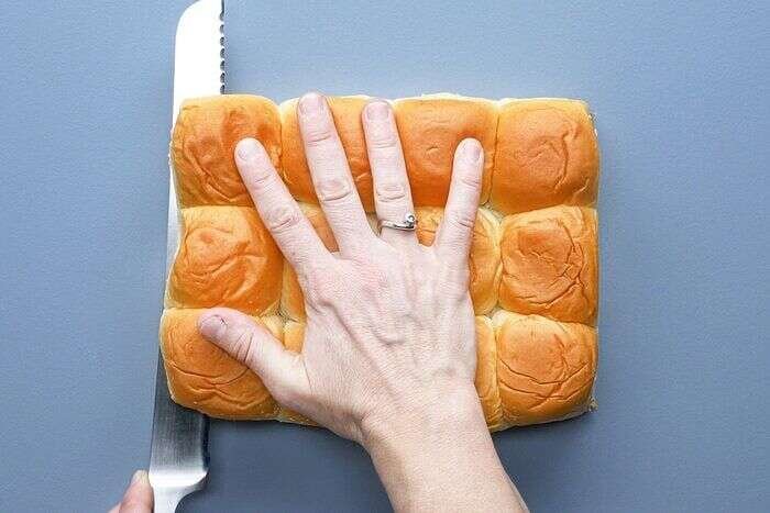Cutting Hawaiian sweet rolls horizontally for Cuban sliders