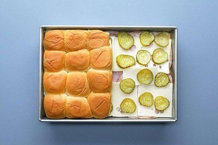 Ham, Swiss cheese, pickles, and rolls layered in a baking pan