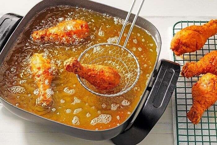 Chicken drumsticks frying until golden brown in hot oil