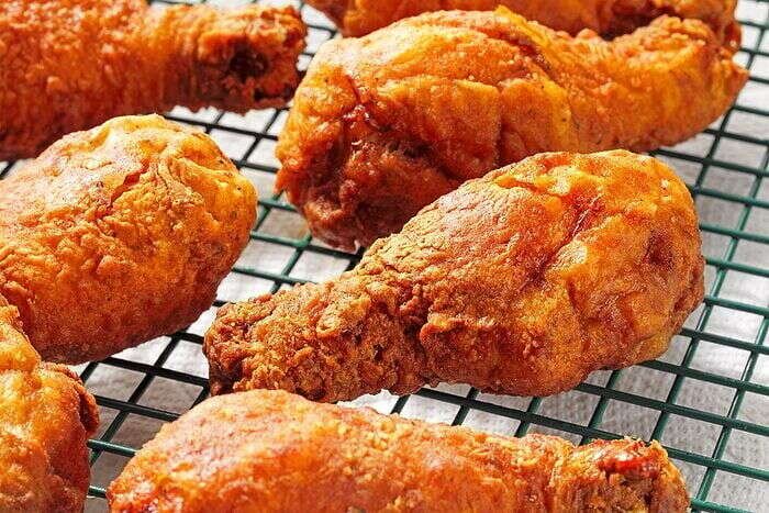 Golden deep-fried chicken legs resting on a wire rack