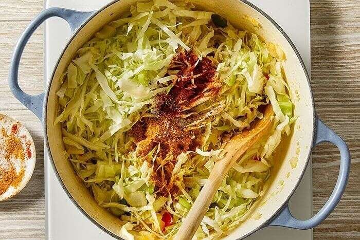 Shredded cabbage seasoned with Cajun spices in a Dutch oven