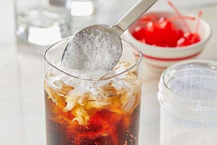 Cold foam being added to a glass of copycat McDonald’s Dirty Dr Pepper