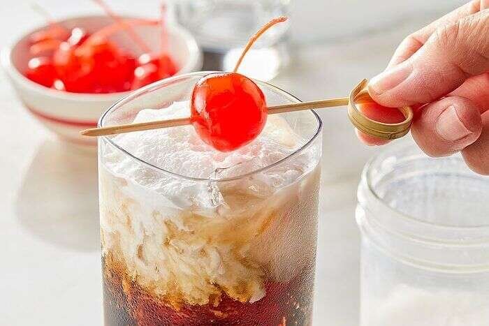 Maraschino cherry added to a layered Dirty Dr Pepper drink