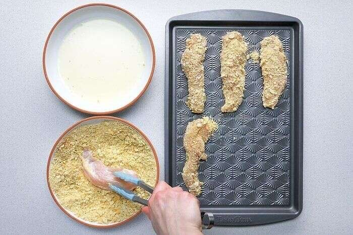 Chicken strips coated in egg mixture and seasoned cracker breading