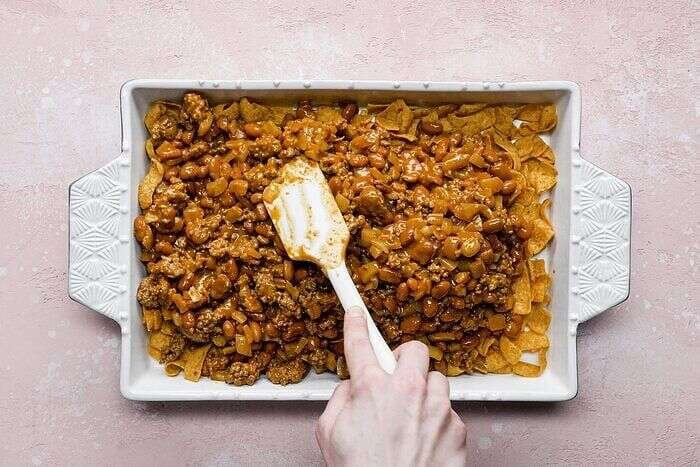 Beef and bean mixture layered over Fritos in a baking dish