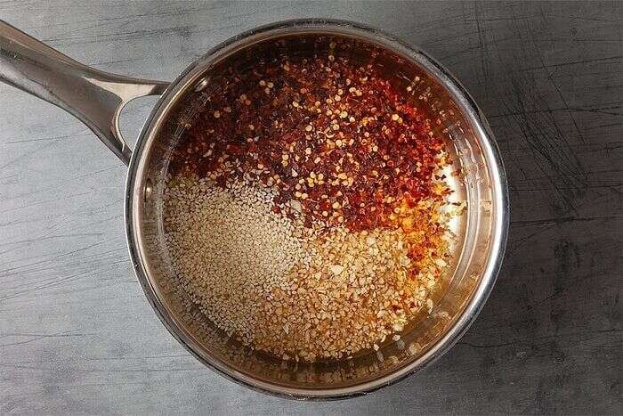 Chili crisp ingredients warming in oil in a saucepan