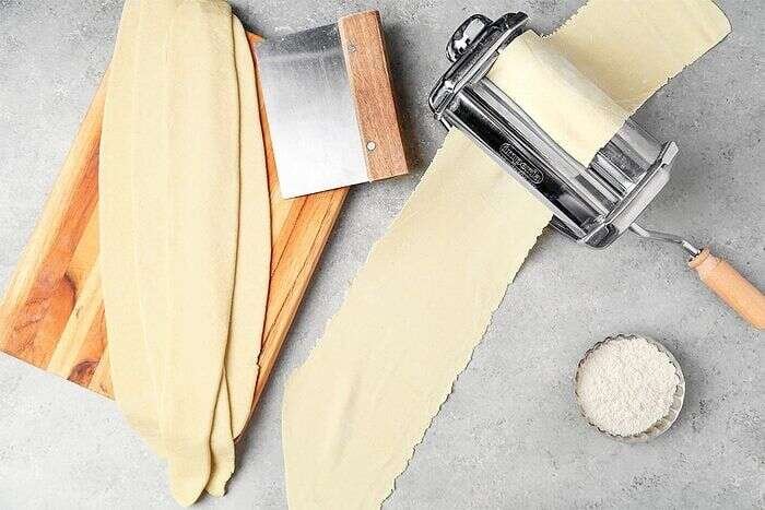 Thin ramen dough sheets passing through a pasta roller