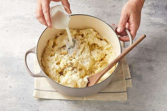 Adding milk to creamy mashed potatoes