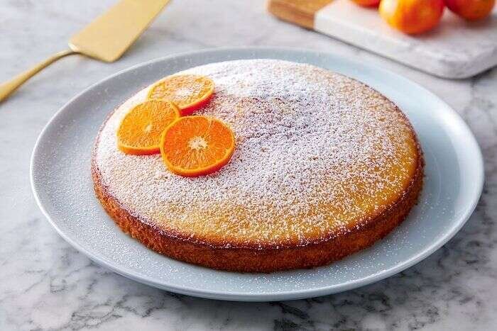 Orange olive oil cake dusted with sugar and served with orange slices
