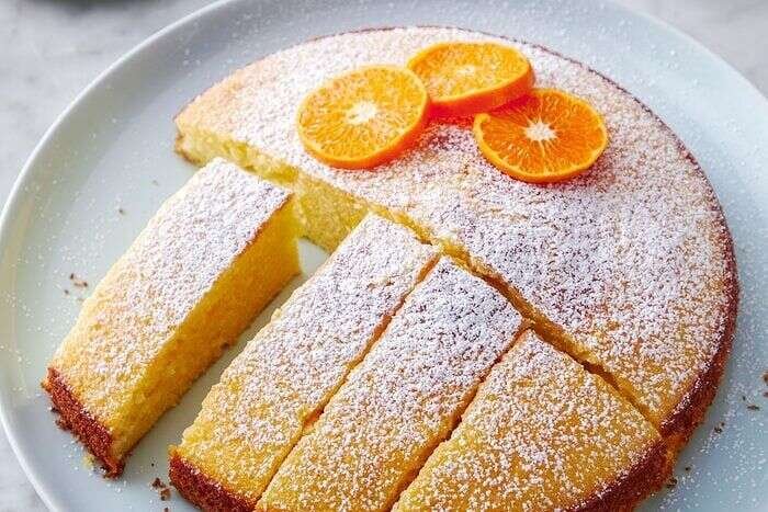 Slices of orange olive oil cake dusted with sugar and served with orange slices