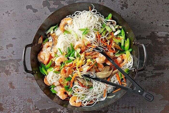 Shrimp and rice noodles added to the wok for mei fun