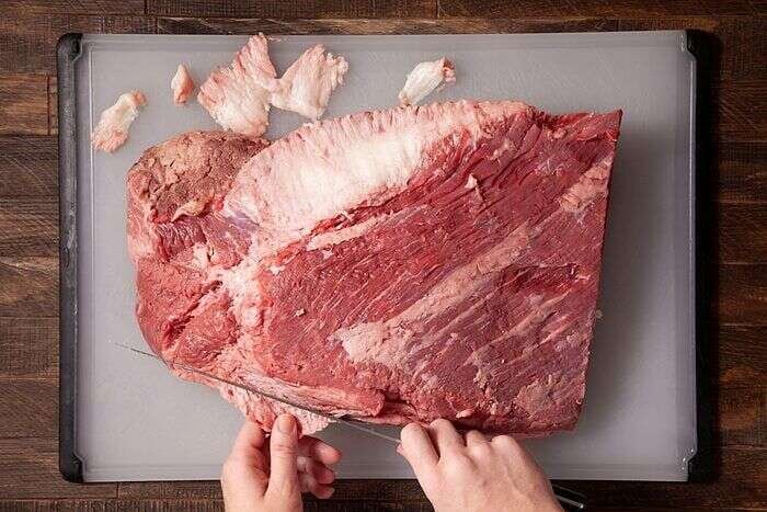 Brisket placed fat side down on a cutting board for trimming