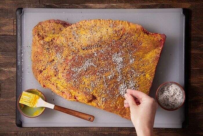 Rubbing kosher salt pepper and onion powder over seasoned beef brisket