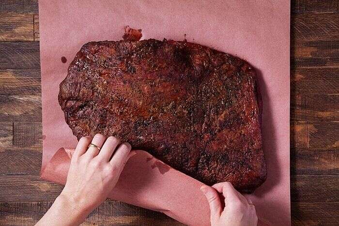 Wrapping smoked brisket securely in unwaxed butcher paper
