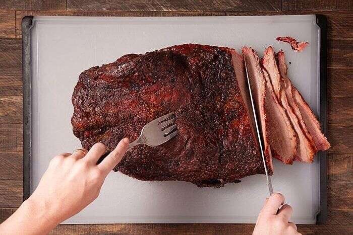 Slicing tender smoked brisket across the grain