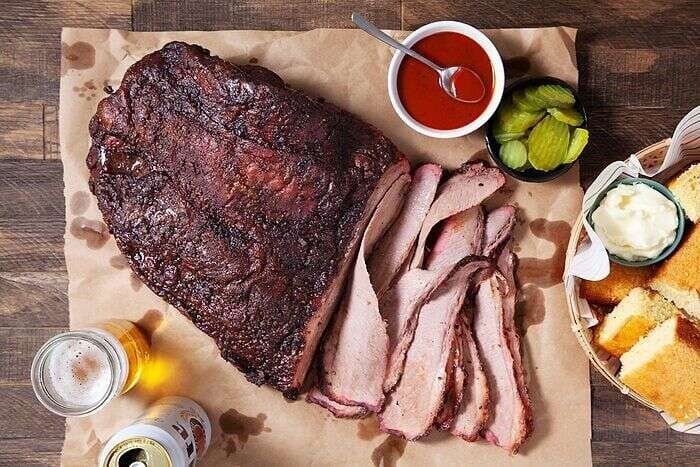 Sliced smoked brisket served with sauce for a barbecue meal