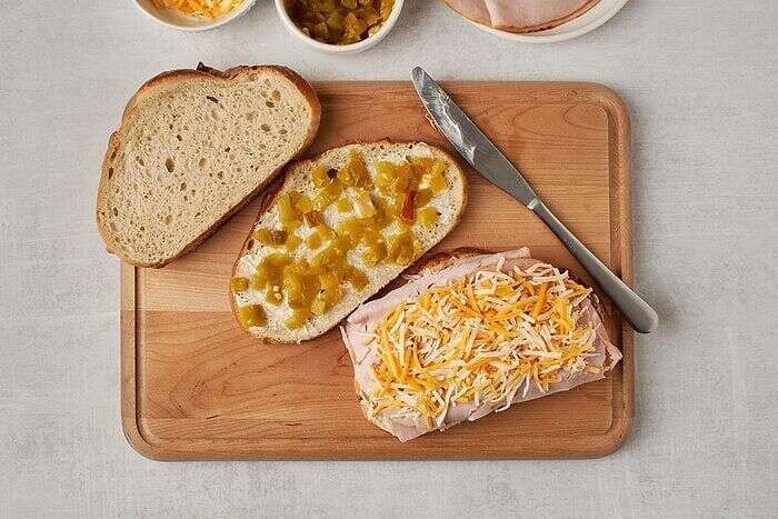 Sourdough turkey melt sandwich being assembled with green chiles and cheese