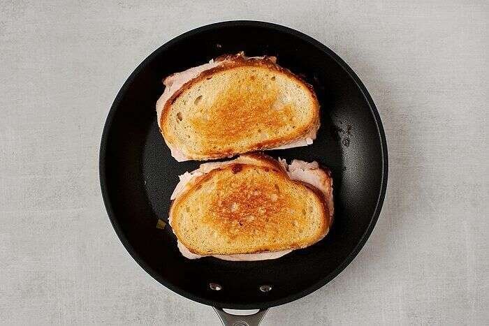 Turkey melt sandwiches grilling in a skillet until golden and crisp