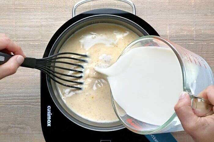 Milk being whisked into the sauce for white cheddar mac and cheese
