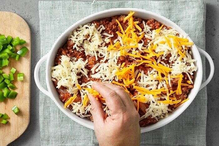 Cheese sprinkled over zucchini pizza casserole before baking